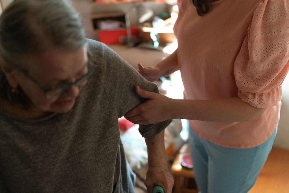 A caregiver supporting an older woman at home